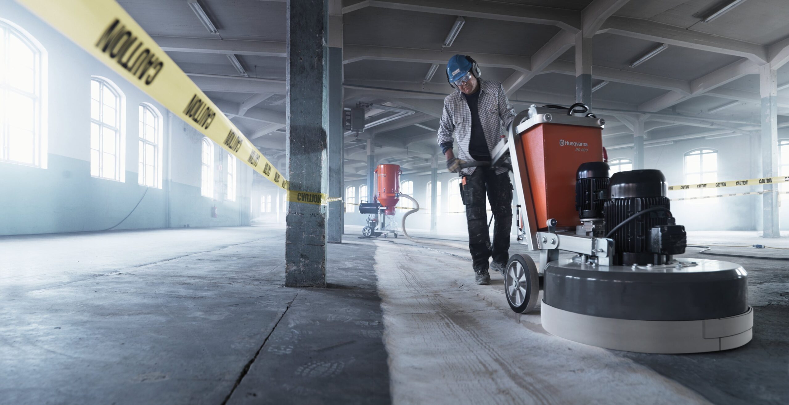 Construction worker using a concrete grinder for indoor floor preparation.